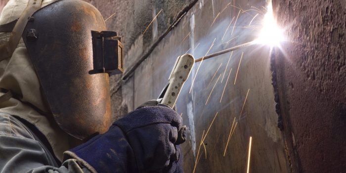 Welding new steel plates on a ship's hull during repair work on a ship in a dry dock.